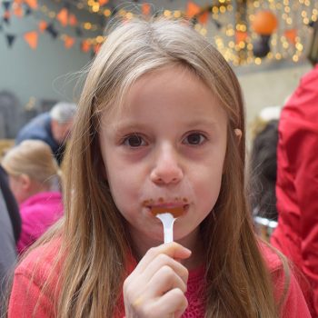 Young girl licking a chocolatey spoon