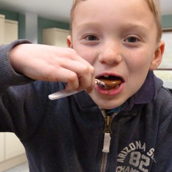 Young lad eating melted chocolate of a plastic spoon